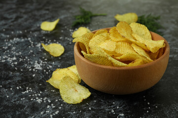 Bowl with potato chips on black smokey background