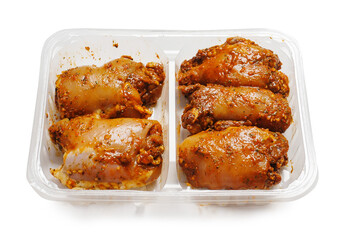 Raw uncooked Asian spice marinated chicken fillets in a plastic tray. Poultry product. Meat industry, Summer barbecue range. Meat in marinade with herb, oils and sauce. Isolated on white