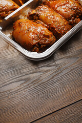 Raw uncooked Asian spice marinated chicken fillets in a plastic tray on a wooden table surface. Poultry product. Meat industry, Summer barbecue range. Meat in marinade with herb, oils and sauce.