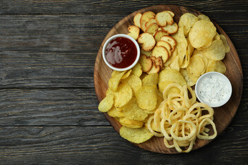 Tray with different snacks on wooden background