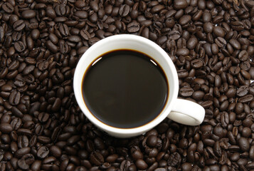 A cup of coffee, coffee beans background, top view