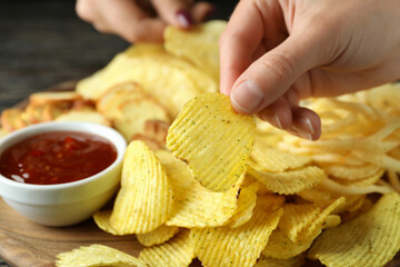 Female hands hold chips over the tray with chips, close up