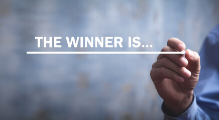 Male hand writes The Winner Is... text in screen.