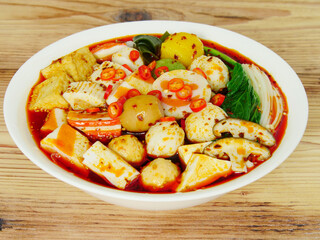 Hot pot is also called Mala Tang, tofu bubble, vegetables, mushrooms, meatballs, red pepper and kelp, wooden texture background