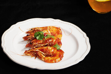 Fried shrimps with soy sauce in white plate, seafood, black background