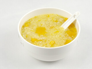 A bowl of nutritious and delicious pumpkin millet porridge with a spoon in it, white background