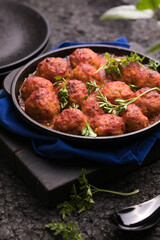 Meat balls with tomato sauce  in a frying pan on a black background.