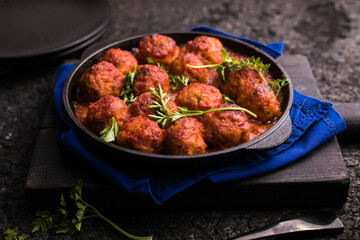 Meat balls with tomato sauce  in a frying pan on a black background.