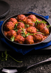 Meat balls with tomato sauce  in a frying pan on a black background.