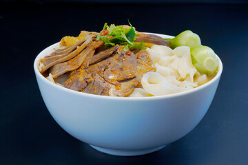 Close-up a bowl of beef noodles with vegetables and beef on, black background