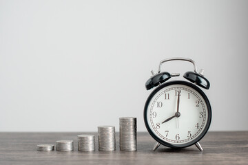 Alarm clock and Money coin stack on oak table