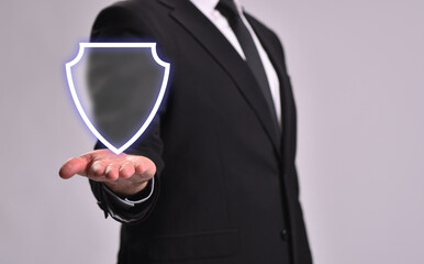 Man in a business suit shows a shield, the concept of protection and guarding.