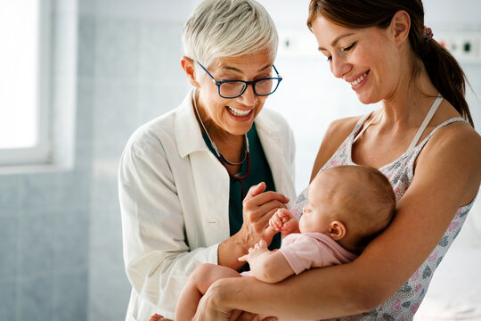 Mother holding baby for pediatrician doctor to examine