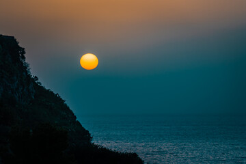 Minimalistic sunrise over the sea. Teal and orange theme, copy space 