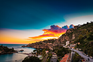 Colorful sunset sky over the bay of Isola Bella- a little island on the Mediterranean coast in Italy 