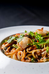 Sea food wok stir fry served in a white plate. Clams and shrimps wok isolated on black.