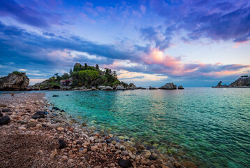 Turquoise water and violet sunset sky on the beach of Isola bella in Taormina, Sicily