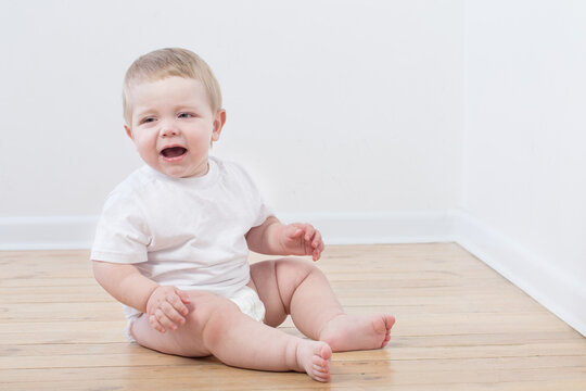 Baby Crying Sitting On Wooden Floor