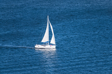 aerial view of a generic white sailboat with two sails sailing on very calm water in the San Diego...