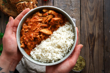 Traditional curry and ingredients. Tikka Masala chicken and rice. Indian food. Top view. Copy space. Wooden background. Hand and food