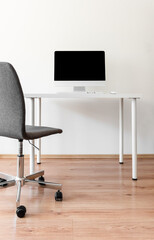 Minimalist home office with a computer on a white desk.