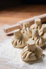 Georgian dumplings Khinkali with meat, on a wooden board with flour, black background.