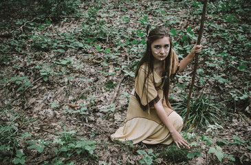 Apache tribe scout looking for tracks in the woods, beautiful native american female warrior looking for footprints in the forest, indian dress concept