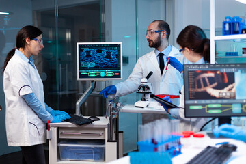 Research scientists working on monitor analyzing virus with chemistry team. Chemists in pharmaceutical lab examining sample for medical experiment with technology for medicine industry.