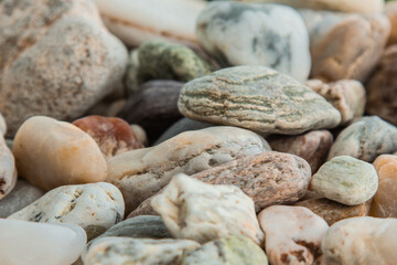 multicolored river pebbles stones randomly lie on the sand next to the sea. Macro photography. Close-up background concept, copy space