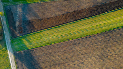 Aerial view geometric farming fields, showing a green meadow and plowed fields, captured with a...