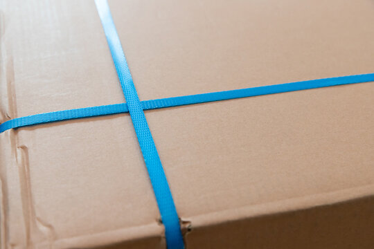 blue packaging straps on brown parcel. freight parcel with plastic belt fastener.