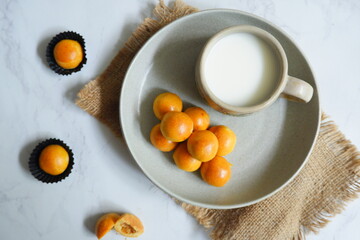 a plate of pineapple tart served with fresh milk on the table