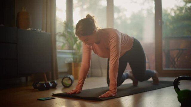 Beautiful Girl Doing Fitness at Home, Setting Mobile Smartphone Timer. Authentic Plus Size Woman Doing Workout, Mountain Climber Steps, Yoga Exercises. Healthy Fit Confident Female. Sunny Living Room