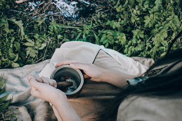 Indian shaman preparing healing potion near a fire outdoors, beautiful woman making health potion near a bonfire and herbs, traditional medicine concept