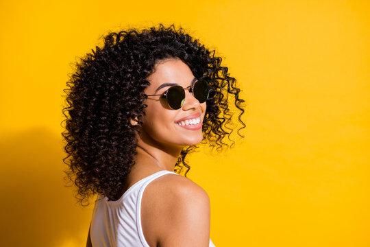Turned photo of charming afro american woman happy smile wear white tank-top isolated on vibrant yellow color background