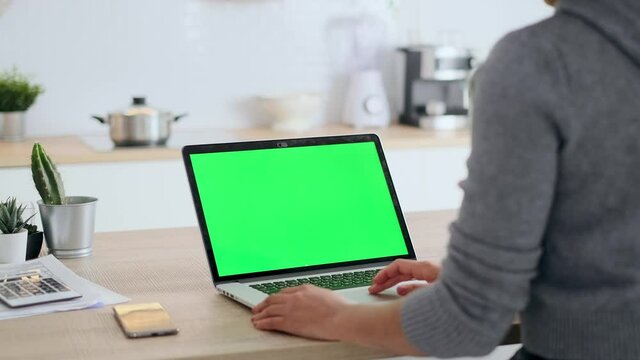 Video Of Afro Business Woman Using Laptop Computer With A Green Screen On Monitor In The Kitchen At Home.