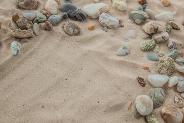 multicolored river pebbles stones randomly lie on the sand next to the sea. Macro photography. Close-up background concept, copy space