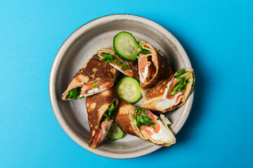 Stack of pancakes with salted salmon and cream cheese Philadelphia in a bowl. Over bright blue background.