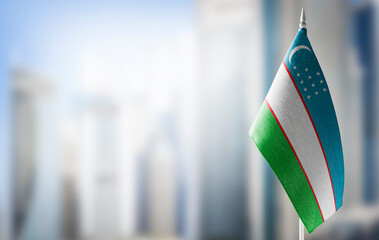 A small flag of Uzbekistan on the background of a blurred background - obrazy, fototapety, plakaty
