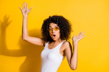 Portrait of impressed dark skin lady open mouth raise hands palms clubbing isolated on yellow color background