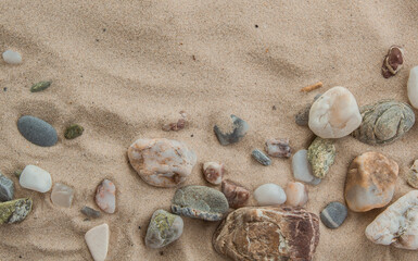 multicolored river pebbles stones randomly lie on the sand next to the sea. Macro photography. Close-up background concept, copy space