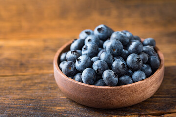 Organic blueberries in a wooden bowl on old wooden table background with copy space for text, design