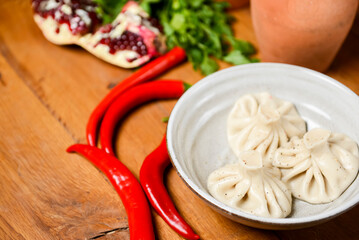 Khinkali cooked on a ceramic plate over rustic wooden background.