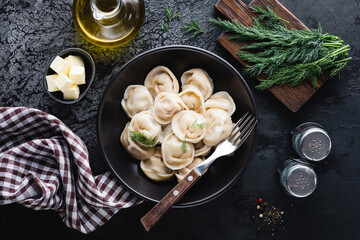 Dumplings stuffed with meat, russian pelmeni with dill in a bowl, top view