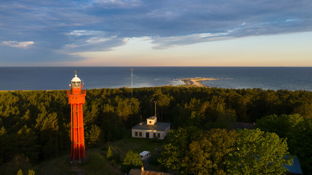 Aerial view to the historic lighthouse rising over woodland and seascape, painted by the golden morning sunlight 