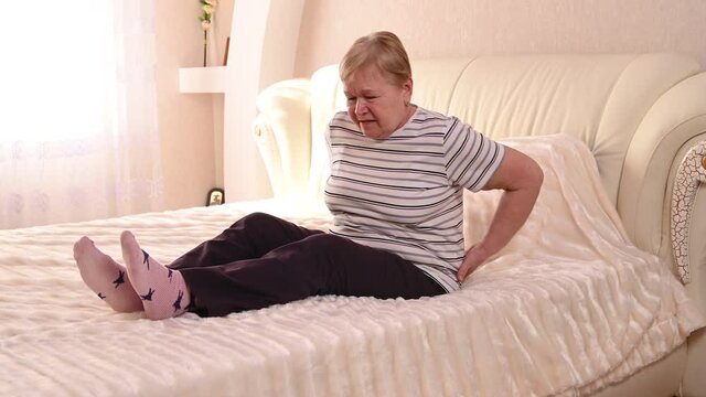 Elderly woman on bed with back pain 