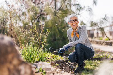 Portrait of a smiling senior woman working in the garden in the spring.