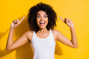 Photo of excited funny young dark skin woman dressed white tank-top pointing up empty space isolated yellow color background