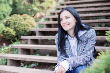 Obraz premium Portrait of young brunette woman in plaid coat in park enjoying the nature