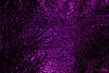Abstract purple aluminum wrinkled foil background texture reflecting purple light